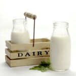 Two glass jars with fresh milk with a wooden box